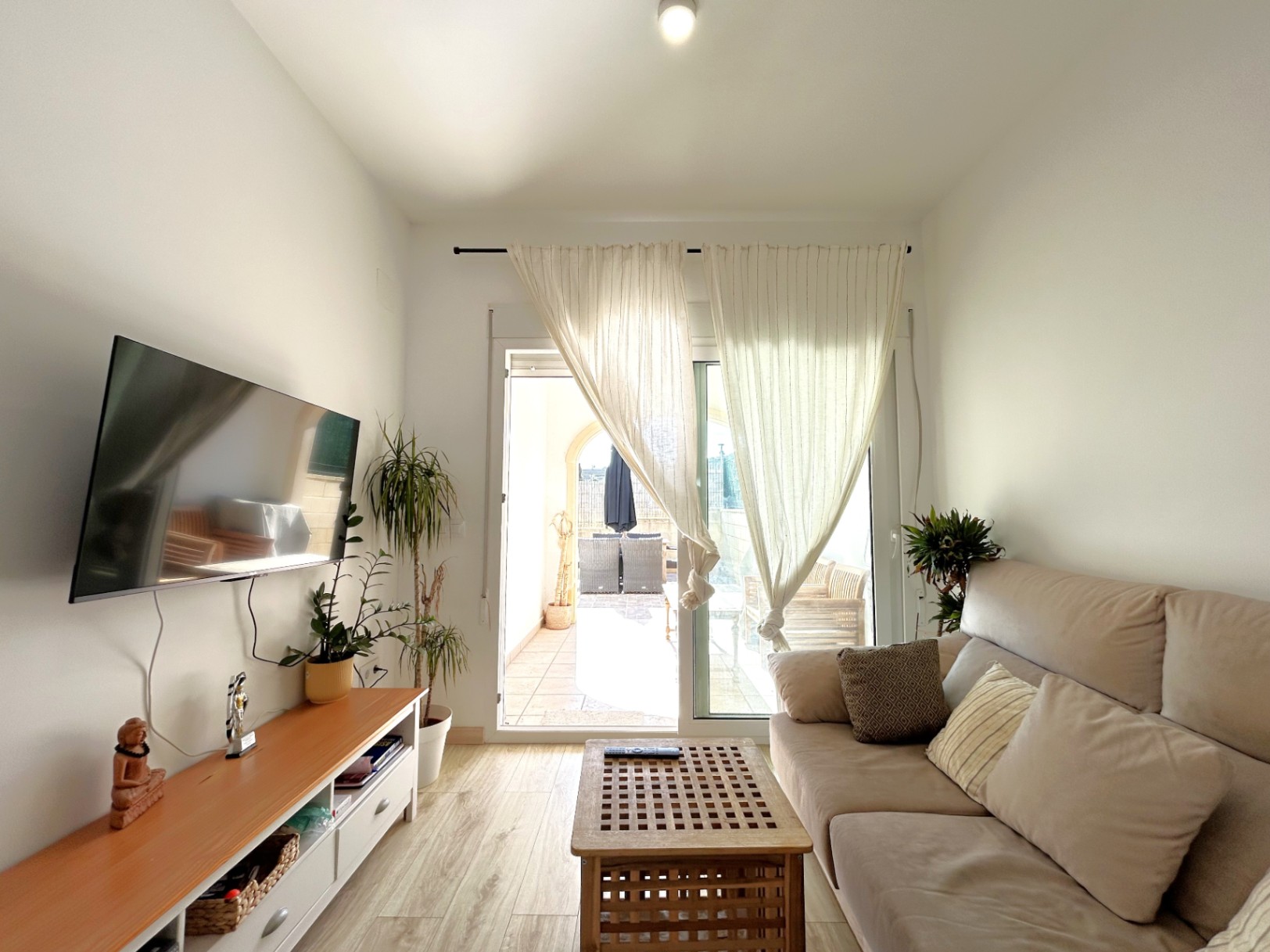 Lichte woonkamer met directe toegang tot het privéterras via glazen schuifdeuren, voorzien van een houtlook vloer.