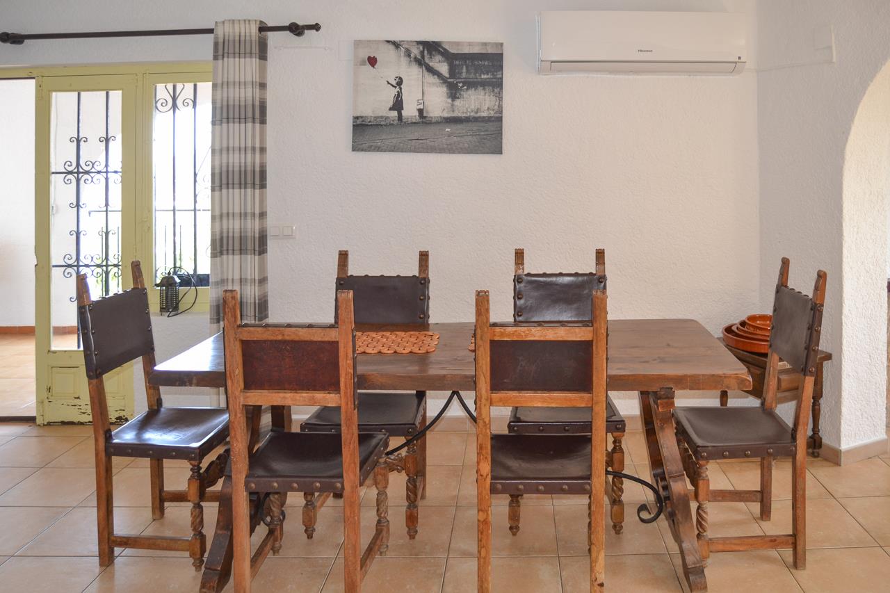 Eethoek met een massief houten tafel en rustieke lederen stoelen. Voorzien van een split-airconditioning en toegang tot de aangrenzende ruimtes.