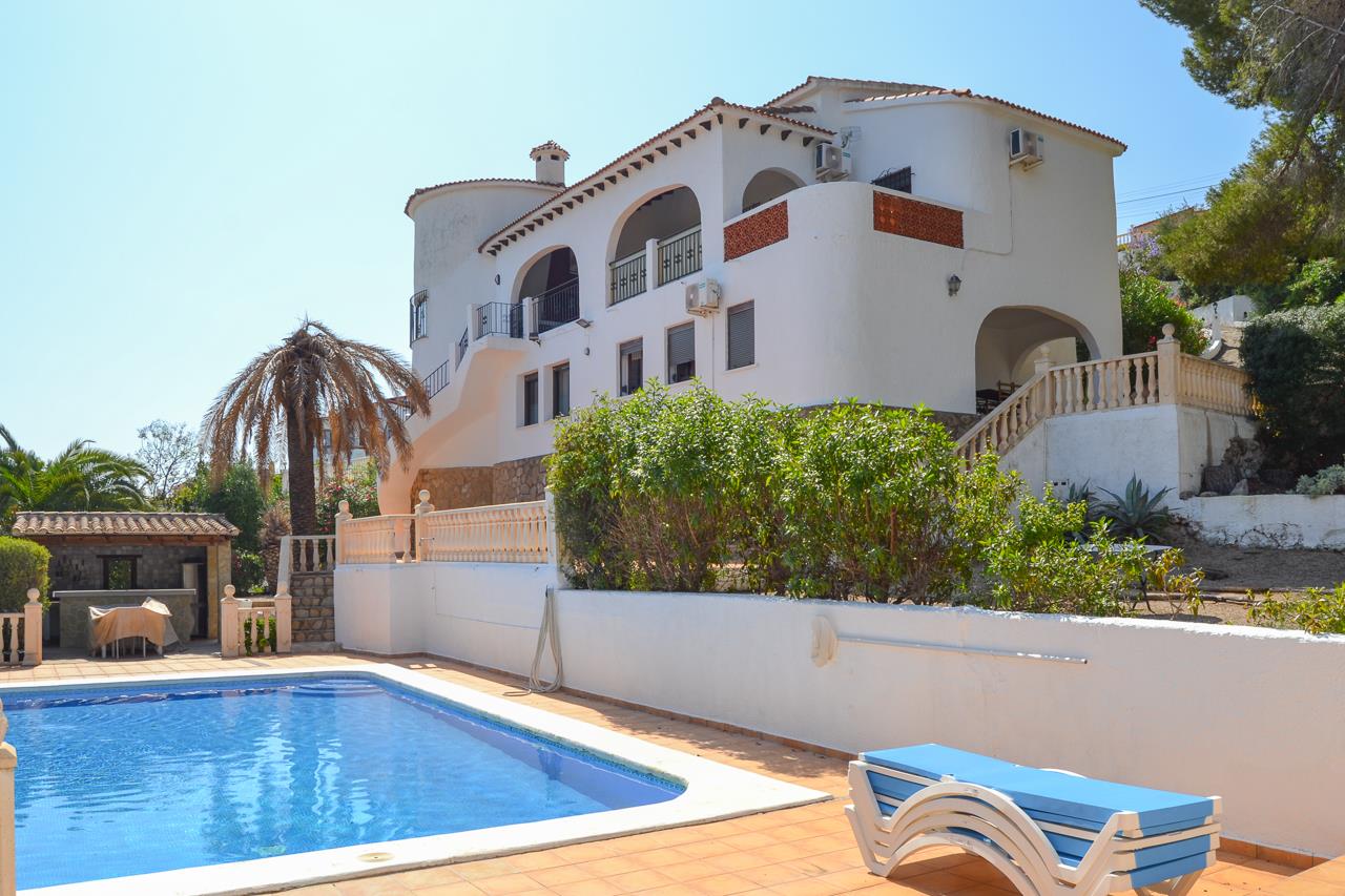 Exterieur van de witte mediterrane villa met een groot zwembad, ruime zonneterrassen en karakteristieke bogen in de gevel.
