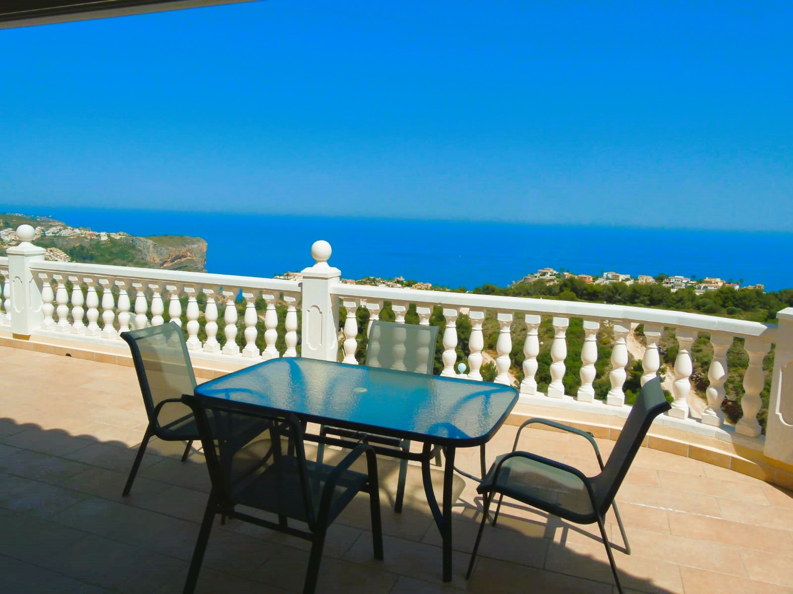 Terras met glazen tafel en zeezicht in Cumbre del Sol. Witte balustrade.