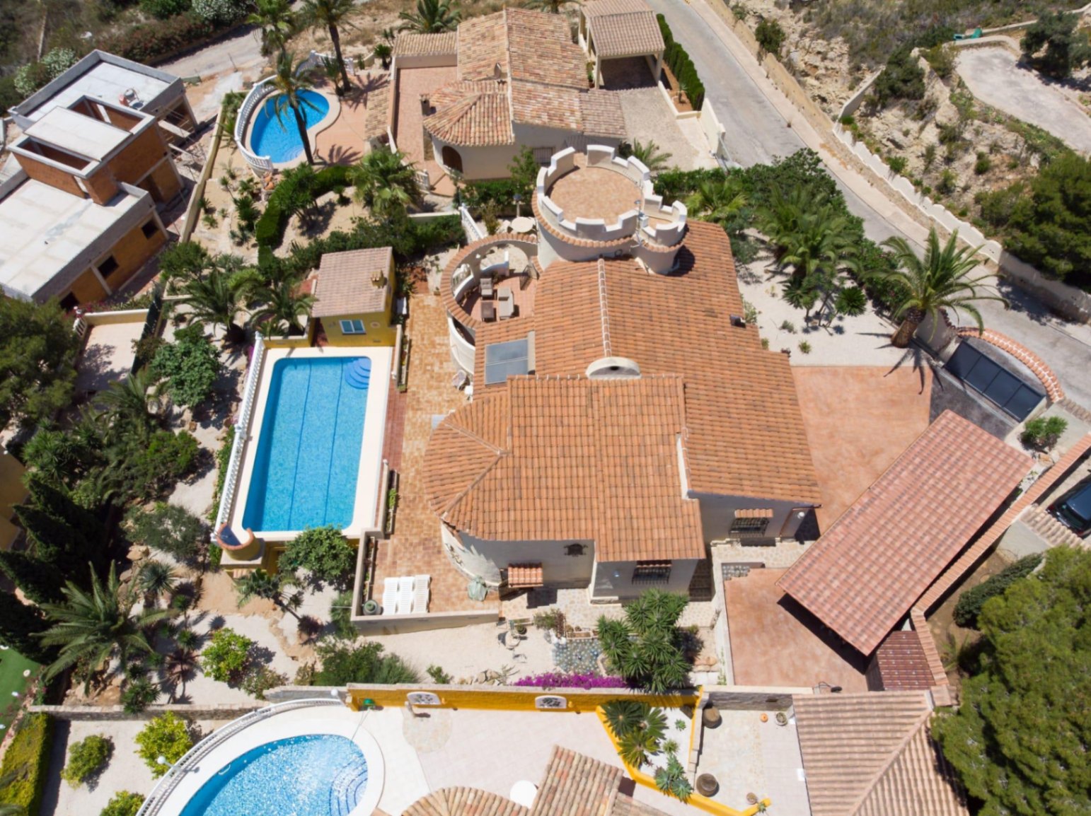Luchtfoto van de villa met de kenmerkende torenarchitectuur, het 10x4 meter zwembad en de ruime terrassen omgeven door een mediterrane tuin.