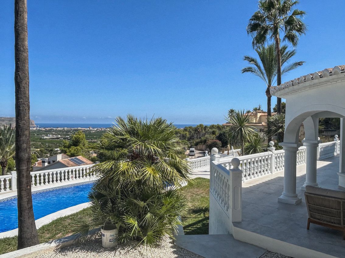 Overdekt terras met bogen en witte balustrades met panoramisch uitzicht op zee en de vallei, gelegen naast het privézwembad en de mediterrane tuin.