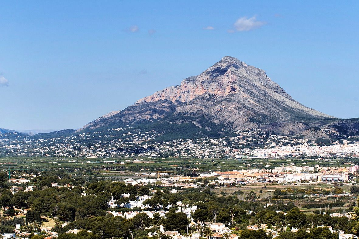 Panoramisch uitzicht op de berg Montgó en de vallei van Jávea, met het mediterrane landschap en de omliggende woonwijken onder een heldere hemel.