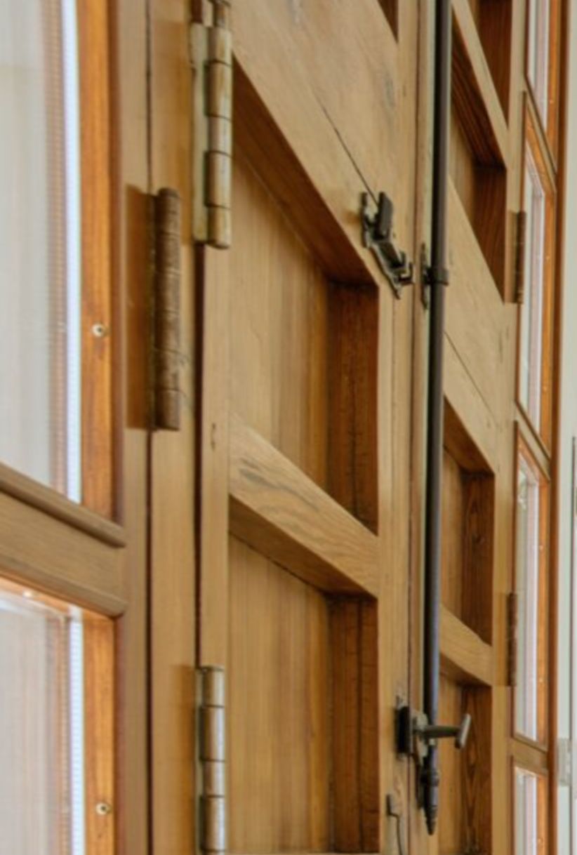 Detail van massief houten schrijnwerk met traditionele metalen scharnieren en een espagnoletsluiting, kenmerkend voor de hoogwaardige afwerking van de villa.