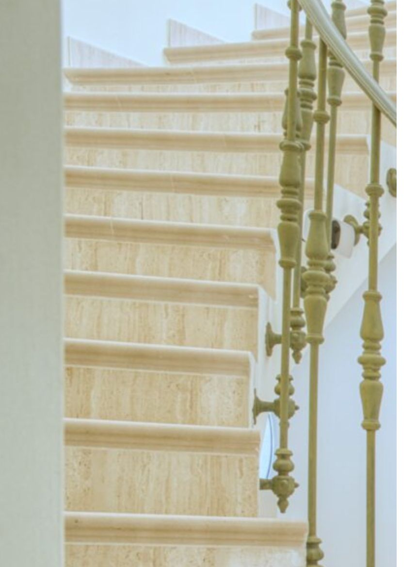 Natuurstenen trap met gepolijste marmeren treden en een sierlijke klassieke metalen balustrade die de verdiepingen van de villa elegant verbindt.